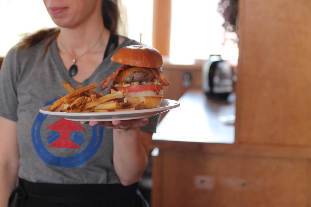 waitress carrying piled high burger and fries