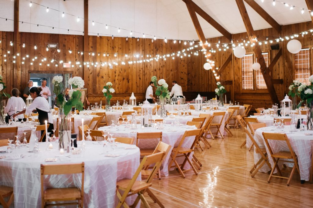 Decorated Town Hall for wedding reception with round tables, linen table cloths, lighting and flower arrangements
