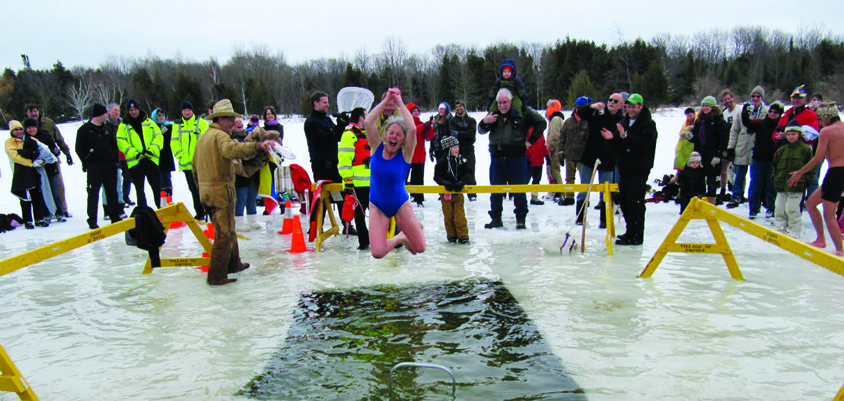 woman jumping into icy lake water for winter fest polar plunge